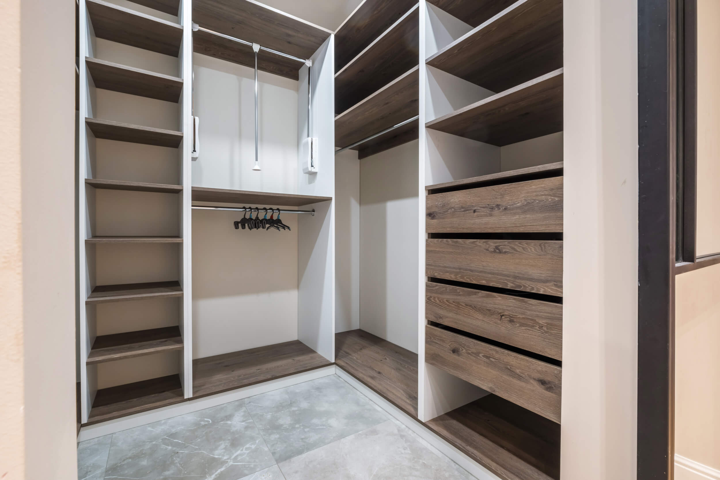 rows of shelves and clothes hangers in the wardrobe. empty big wardrobe room in modern apartment or hotel
